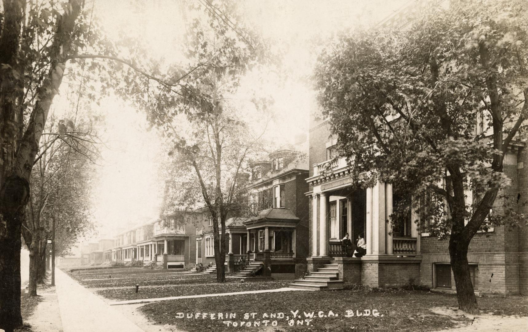 Black and white photograph of two story homes lining a city street.