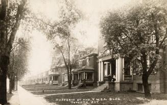 Black and white photograph of two story homes lining a city street.