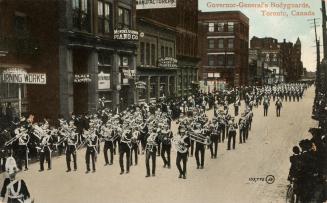 Colorized photograph of men in military uniforms parading on a city street playing musical inst…