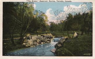 Colorized photograph of a stream with a waterfall in a wooded area.