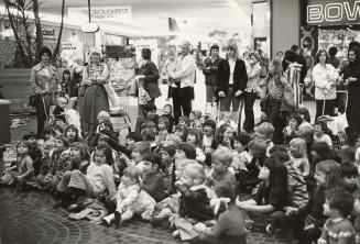 Picture of large audience of children at a library event in a mall. 