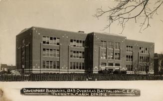 Black and white photo postcard depicting the exterior of a large three-story building with hund ...