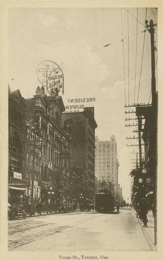 Black and white photo postcard depicting a view of Yonge St. with some buildings, retail shops, ...