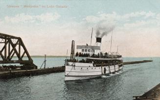 Color photograph of a large boat in water beside a bridge.