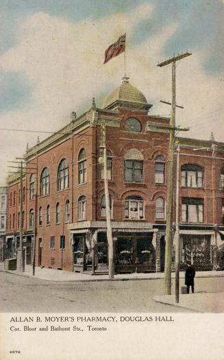 Colour postcard depicting the corner view of a three-story building with flag on its rooftop an ...