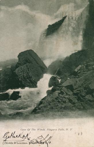 Black and white photograph of high waterfall with a stone pathway in front of it.