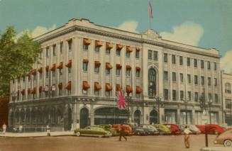 Color photograph of a four story public building with automobiles parked in front of it.