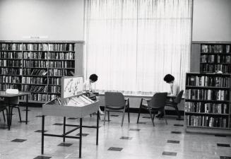 Picture of interior of library with two people sitting in chairs. 