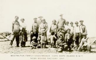 Black and white photograph of eighteen members of an Inuit family and two mounted police office ...