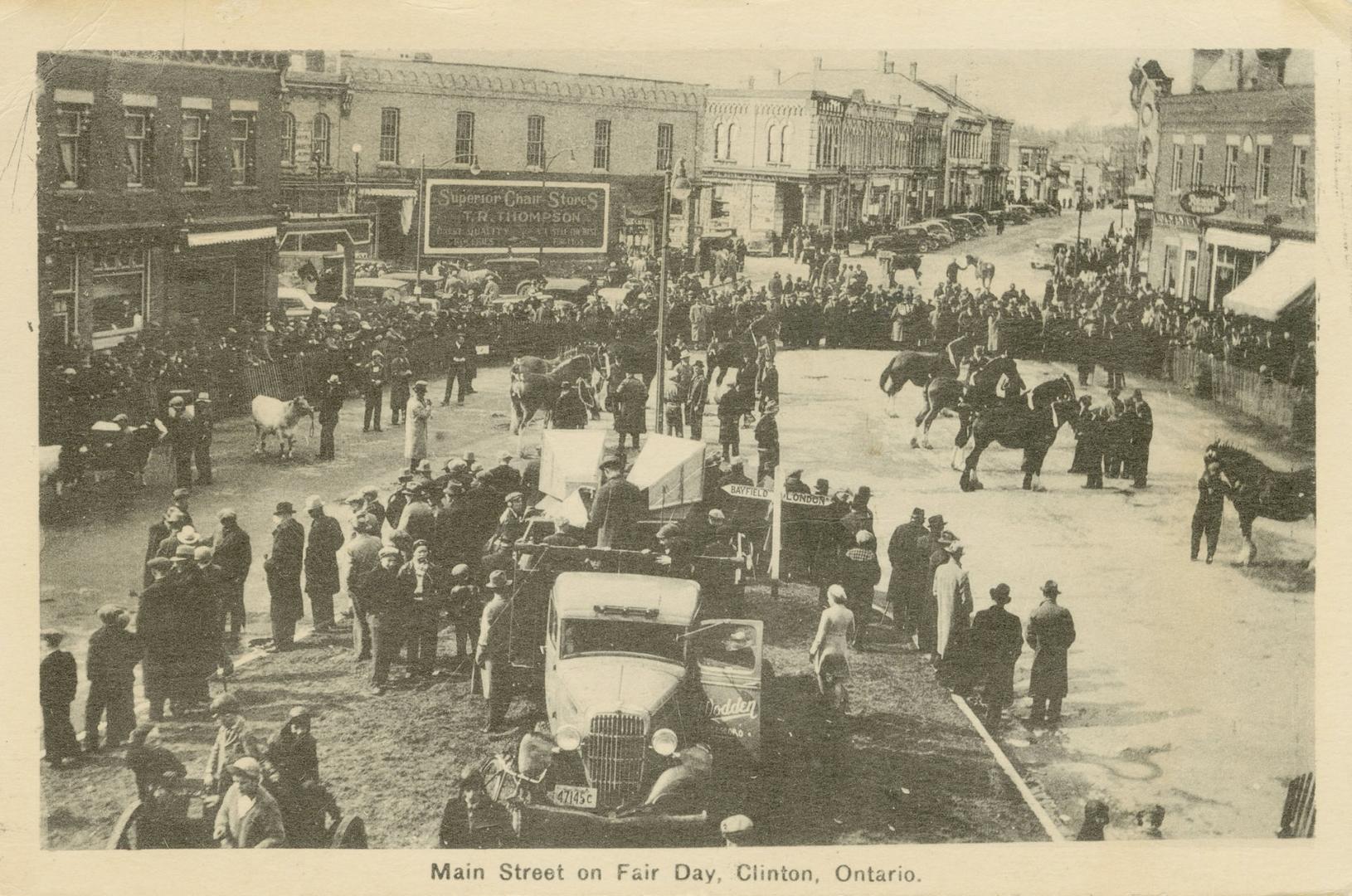 Black and white photograph of a busy parade on a downtown street.