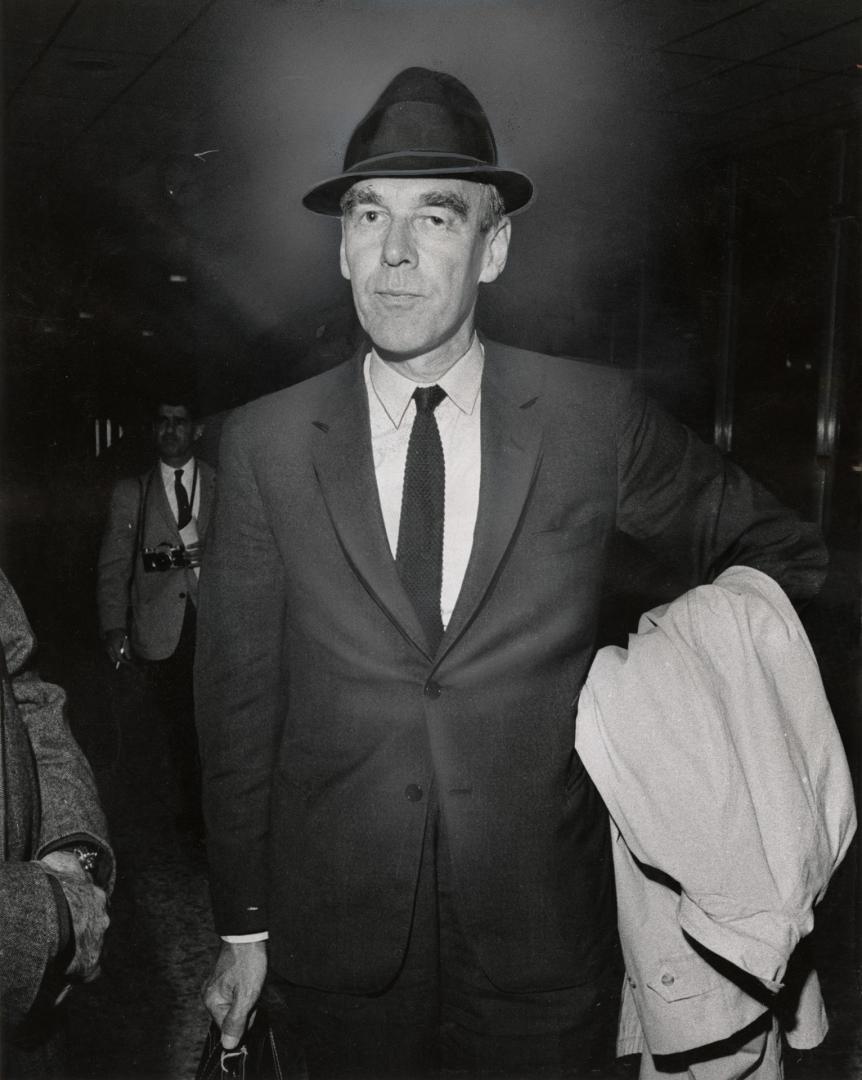 Portrait of older white man in suit and hat carrying briefcase