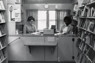 Picture of the interior a bookmobile with two staff seated at a desk