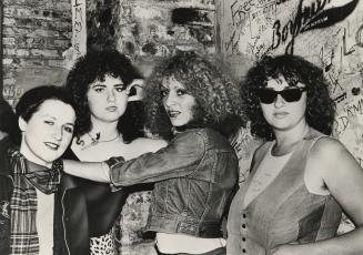 Four young woman against graffiti strewn walls. 