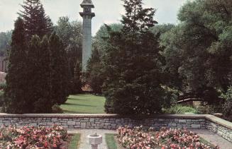 Color photograph of roses with a walled garden, chimney as a feature in the background.