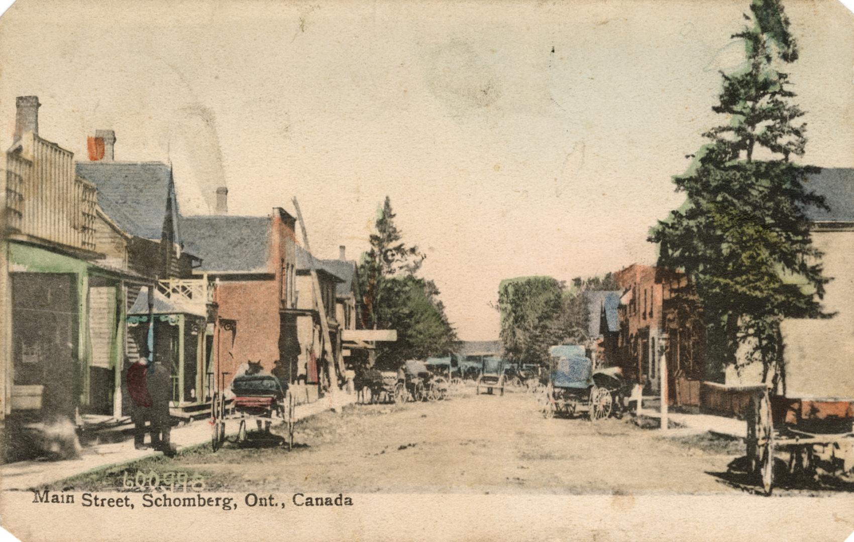 Colorized photograph of buildings and horse and buggies lining a street of a small town.