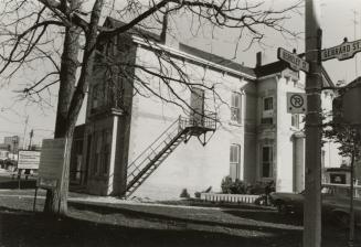 Picture of a Victorian house from the side view and construction signs out front. 