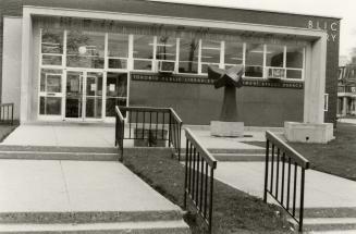 Picture of one storey library building with sculpture out front. 