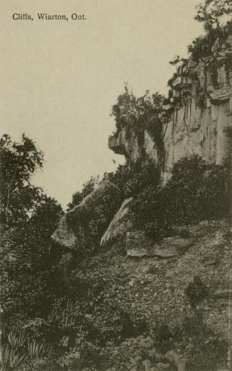 Black and white photograph of high, rocky cliff.