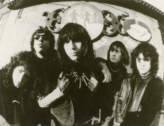 Sunny day, fish eye view. Five dark long,dark-haired young men in black leather and black tops …
