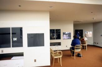Picture of person sitting in an area with several screens watching a film. 