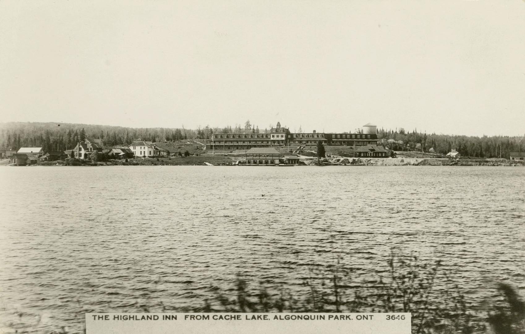 Black and white photograph of a body of water with a large hotel on the opposite shore.