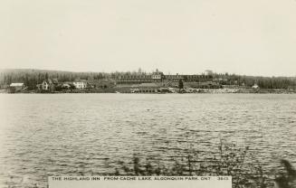 Black and white photograph of a body of water with a large hotel on the opposite shore.