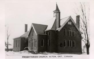 Black and white photograph of two story country church of late Victorian architecture with snow…