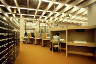 Picture of a row of study carrels on the right and large black microfilm cabinets on the left s…