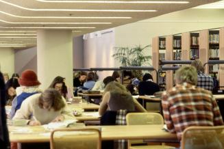 Picture of people sitting studying at tables in a library. 