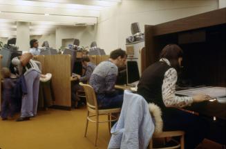 Picture of people reading newspapers at a carrel and microform equipment. 