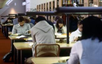 Picture of people seated at library tables studying. 