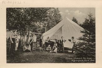 Black and white photograph of men and boys doing nature activities in front of a large tent in …