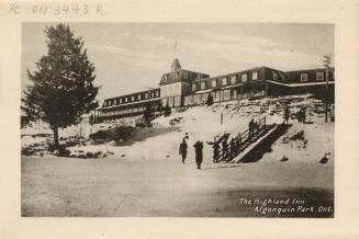 Black and white photograph of a group of people climbing up stairs towards a long, two-story ho…