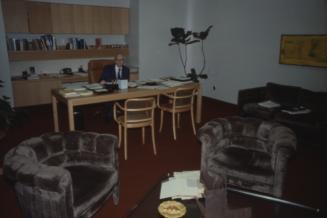 Picture of a man at a desk in an office area. 
