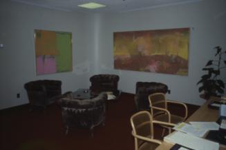 Picture of chairs in an office area and two large abstract painting on the walls. 