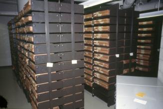 Picture of black shelving units full of bound newspapers. 