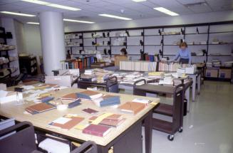 Picture of library work room with large tables and book trucks. 