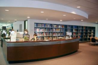 Picture of two librarians at a large reference desk. 