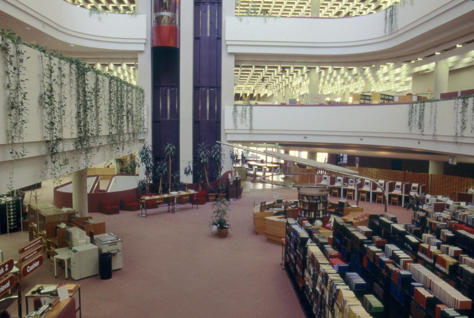 Picture of library atrium looking down at first floor with shelves, table, balconies and glass …