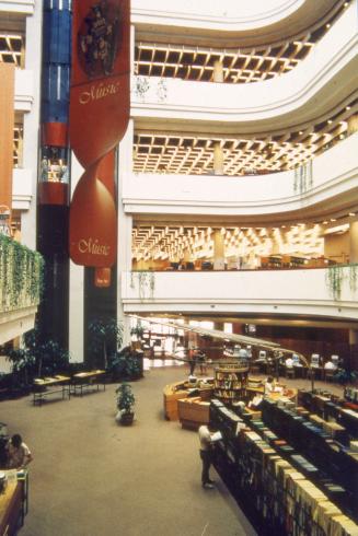 Picture of library atrium looking down at first floor with shelves, table, balconies and glass …