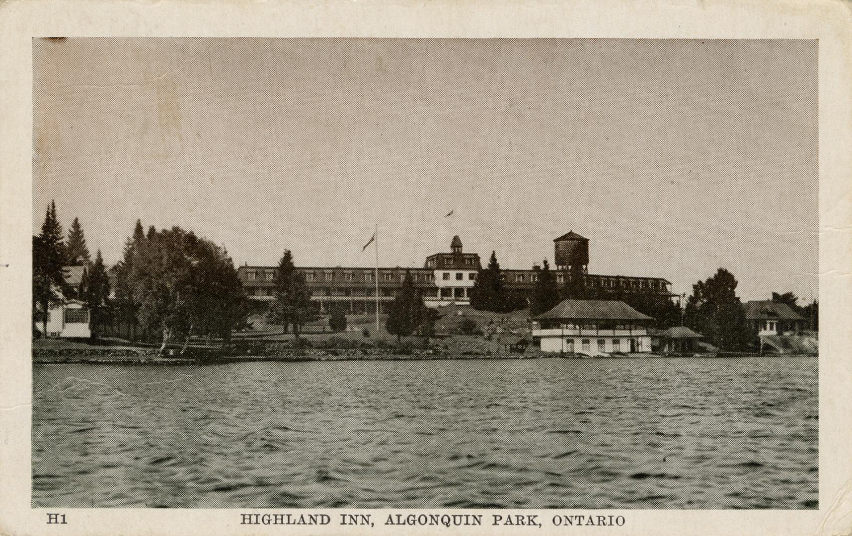 Sepia tone photograph of a three story hotel on the shoreline of a body of water.