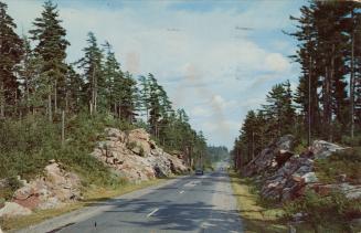 Colour photograph of a two lane highway running through a rock cut.