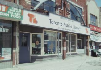 Picture of a storefront library with large sign in orange. 