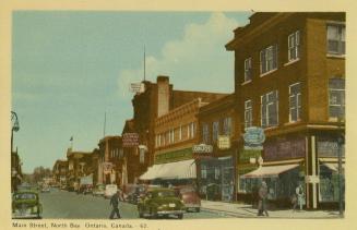 Colorized photograph of a path in a well groomed park leading up to a tall statue.