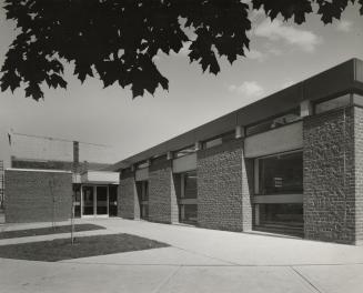 Exterior view of a one storey brick library building. 