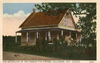Colorized photograph of a two story cabin with an open, wrap around porch.