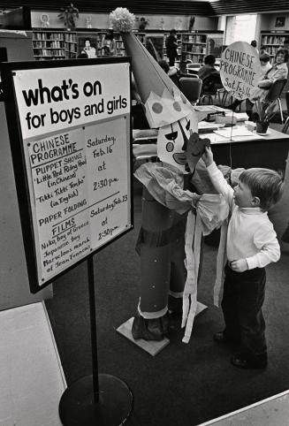 Picture of a small boy placing a heart shaped paper onto a large paper clown next to a sign lis…