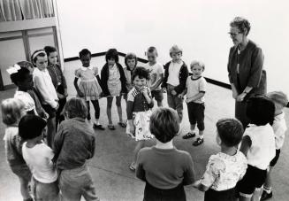 Picture of a group of young children in a circle with a librarian. 