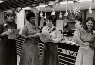 Picture of four staff and a customer standing singing in front of registration desk in a librar…