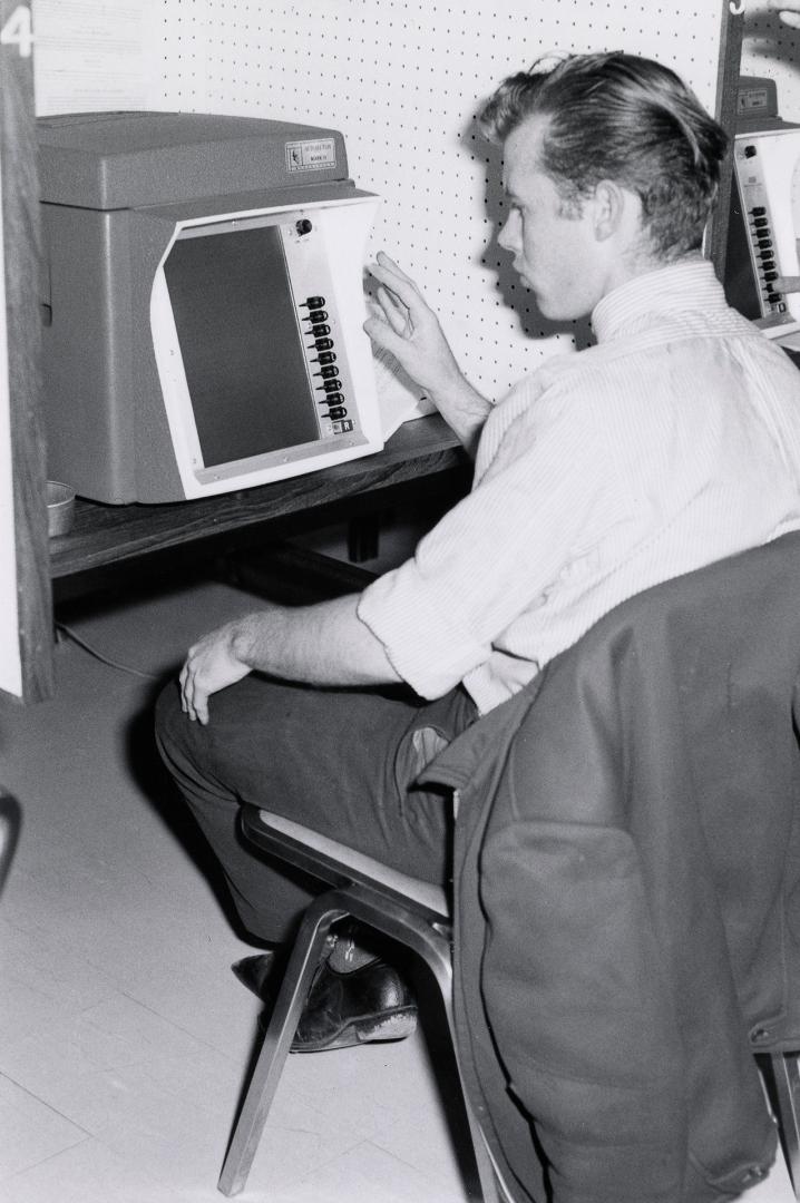 Picture of a person at a library carrel using a piece of equipment. 